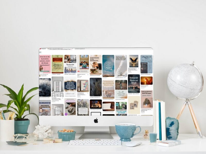 Ein weißer Schreibtisch mit einem Computer, der eine Collage inspirierender Zitate anzeigt. Um den Monitor herum stehen eine Topfpflanze, ein Globus, Bücher, eine Tasse und eine Tastatur und schaffen so einen aufgeräumten und motivierenden Arbeitsplatz.
