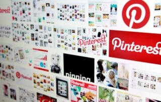 Auf einem Computerbildschirm wird eine Collage aus Pinterest-Logos und verschiedenen Miniaturansichten von Bildern angezeigt, die die Benutzeroberfläche der Pinterest-Website mit ihrem rot-weißen Branding und den leuchtenden Farben präsentieren.