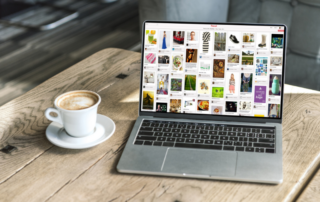 Auf einem Holztisch steht neben einer Tasse Kaffee ein Laptop, auf dem ein Feed zur Pinterest-Strategie angezeigt wird.