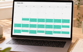 Ein Laptop, auf dem ein digitaler Kalender für Oktober 2026 angezeigt wird, in dem vom 12. bis zum 31. mehrere Termine pro Tag eingetragen sind.